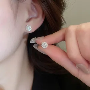 Elegant gold sunflower stud earrings featuring radiant white zircon stones on a model
