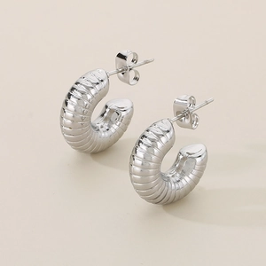 Macro detail of silver C-shaped croissant earrings with textured hollow design and smooth finish