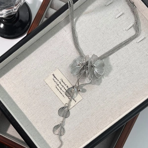 Vintage floral necklace with metal fringe and multi-strand chains on a jewelry box