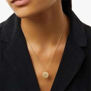 Close-up of golden coin necklace featuring floral and mushroom engravings on model