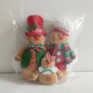 Close-up of three knitted gingerbread man plush dolls with festive red and green details
