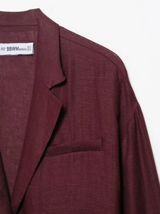 Detail of dark burgundy linen blazer featuring refined stitching and pocket texture