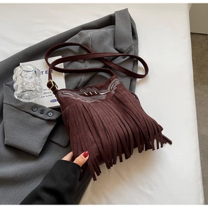 Detail of dark brown faux suede crossbody bag with long tassels and white embroidery