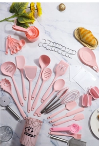 Flat lay macro of a complete pink silicone kitchen utensil set with marble storage bucket
