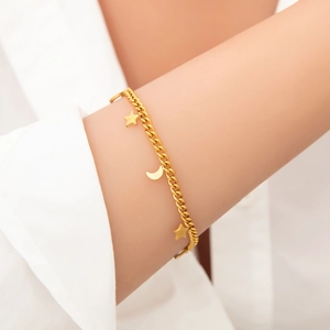 18k gold plated stainless steel bracelet with star and moon charms on model's wrist