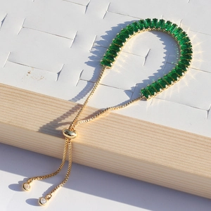 Detail of adjustable gold bracelet featuring emerald green baguette-cut zircon stones