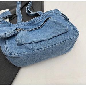 Detail view of denim tote bag with functional front zipper pocket and reinforced stitching