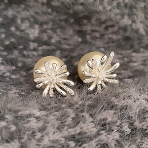 Macro shot of gold-plated pearl earrings with silver flower zircon inlay on velvet