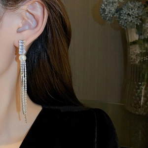 Detail of silver needle tassel earrings with square crystals and a single white pearl