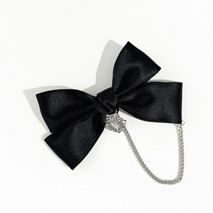 Detail of black satin bow hair clip with silver heart crown pendant and metal chain