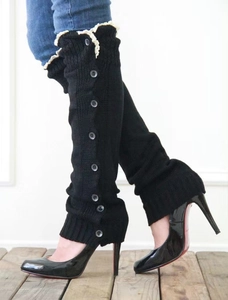 Close-up of black knitted leg warmers with white lace trim and decorative side buttons