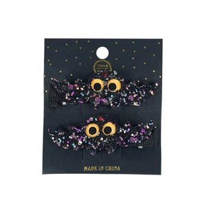 Glittery black bat hair clips for Halloween with large yellow eyes and sequins