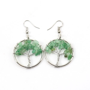 Macro detail of handmade silver wire tree of life earrings with green crystal stones