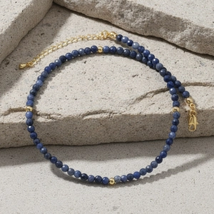 Macro shot of deep blue faceted beads and gold spacers on a textured stone surface