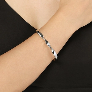 Detail shot of wavy silver stainless steel cuff bracelet worn on a woman wrist