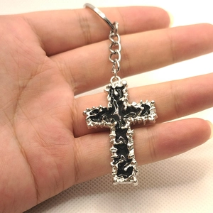 Exquisite silver metal cross keychain with black enamel inlay held in hand