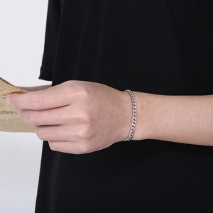 Detail view of a stainless steel Cuban chain bracelet with OT clasp on a male wrist