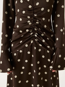 Détails des volants à la taille et des manches trompette sur une robe en satin à pois