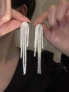 Detail of silver tassel drop earrings featuring shimmering rhinestones in a long chain style