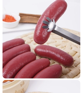 Close-up of stainless steel food tongs with hand-shaped tips grabbing a red sausage