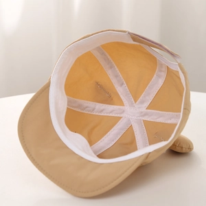 Détail de l'intérieur d'un chapeau bébé montrant la doublure et le tissu beige doux