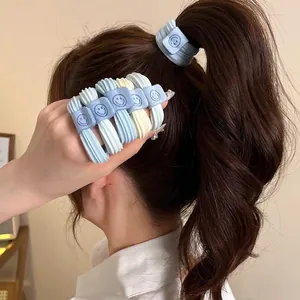 Five elastic sea salt blue hair ties with smiley face labels shown on hand and hair