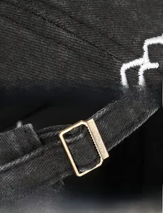 Close-up of black washed baseball cap with mountain embroidery and bronze metal buckle