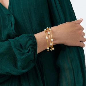 Primo piano di un set di tre braccialetti dorati con perle indossati al polso