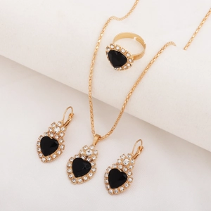 Detail view of gold jewelry set featuring black heart stones and micro-inlaid diamonds