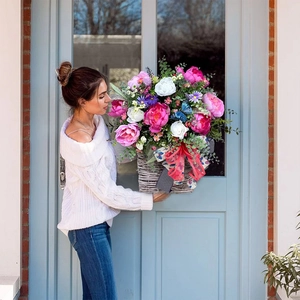 Hanging floral basket with pink peonies, blue butterfly and red bow on blue door decor