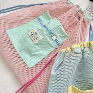 Detail of macaron mesh drawstring bag with pastel pink pocket and happy woven label