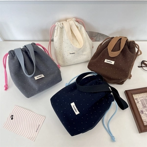 Detailed top view of four polka dot drawstring handbags in grey, beige, brown and navy