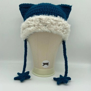Detail view of blue crochet cat ear hat with white plush trim and star tassels