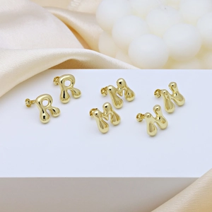 Glossy gold balloon letter earrings R M H displayed on elegant silk background