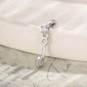 Polished silver cat tail ear stud with heart element and clear gemstone on vintage paper
