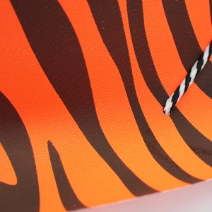 Detail of the orange tiger print party hat texture with a black and white twisted rope handle