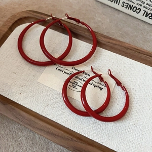 Detailed macro view of two pairs of vintage red hoop earrings in small and large sizes