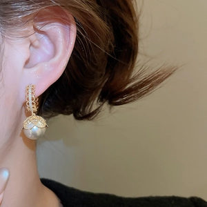 Detail of vintage gold-plated lace earring with zircon and dangling white pearl charm