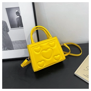Gros plan du sac à main jaune avec motifs cœurs 3D, poignée et bandoulière réglable