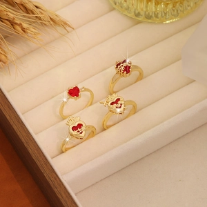 Set of four vintage gold crown and heart rings with red gemstones on a beige display