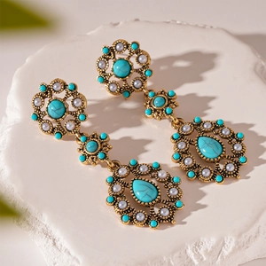Close-up of vintage drop earrings with faux turquoise beads and pearls on stone stand