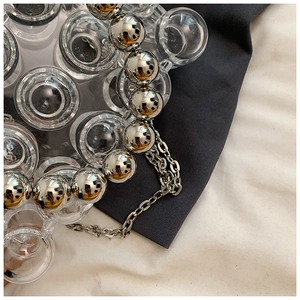 Macro detail of acrylic beads and silver metal spheres on a geometric evening bag