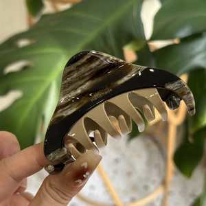 Handheld marble pattern hair claw clip in brown and beige with gold logo emblem