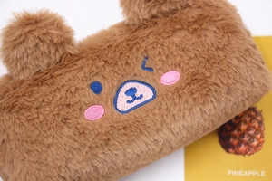 Macro detail of plush brown bear pencil case featuring soft fur and embroidered face