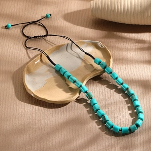 Close-up of turquoise barrel beads on an adjustable black cord ethnic style necklace