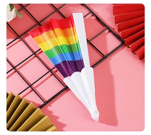Rainbow folding fan with colorful fabric stripes and white plastic ribs on pink background