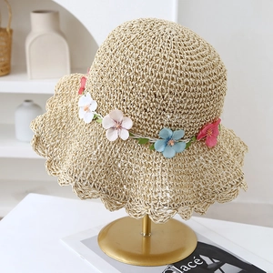 Cappello di paglia beige intrecciato a mano con fiori di stoffa e tesa ondulata estivo