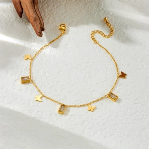 Gold butterfly anklet with cubic zirconia charms on a white textured background