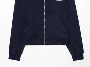 Detail view of navy blue hoodie showing ribbed hem, front pockets and EST. 1975 text