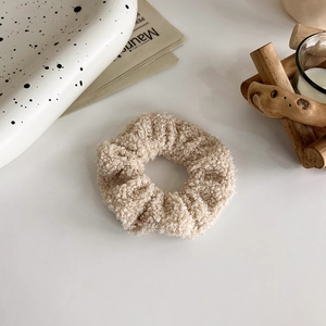 Dettaglio di un elastico per capelli in pile beige su un tavolo in stile moderno
